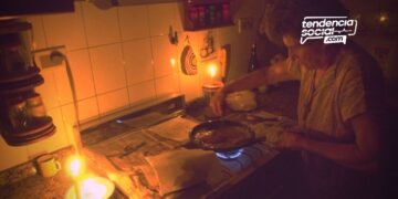 Una mujer en la cocina sin luz con una vela corte de luz en soacha por mantenimiento