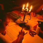 Un niños haciendo tareas en la mesa en medio de unas velas sin luz en Soacha y en la casa