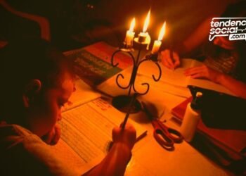 Un niños haciendo tareas en la mesa en medio de unas velas sin luz en Soacha y en la casa