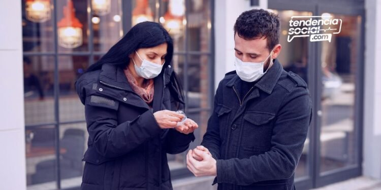 Una pareja hombre y mujer en la calle aplicándose alcohol